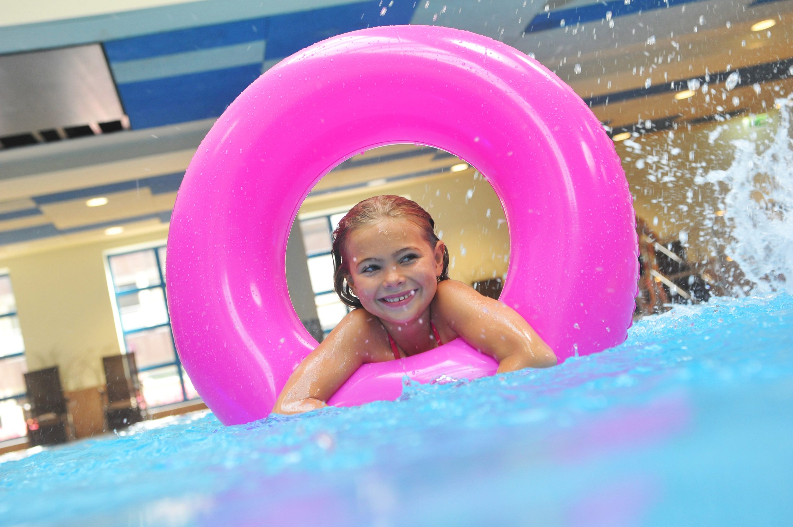 Kind in pinkem Schwimmreifen in Schwimmbad
